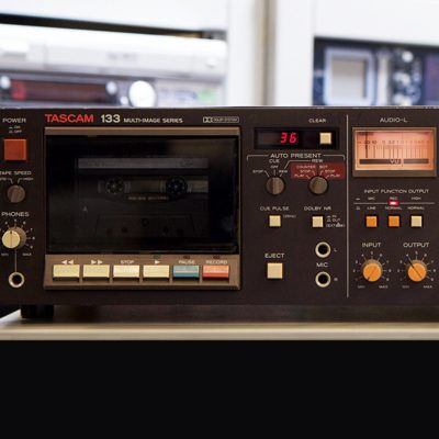 dark brown cassette deck with orange knobs and amber lit VDU meter