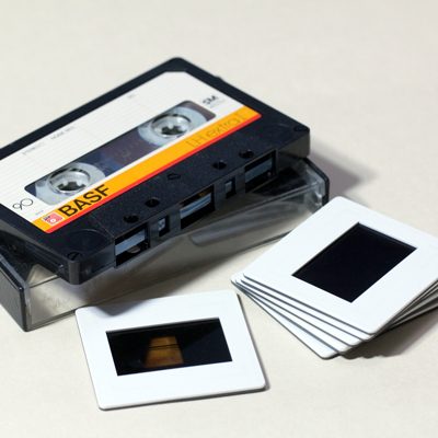 BASF cassette tape resting on plastic box with stack of 6 white plastic-framed colour transparency slides