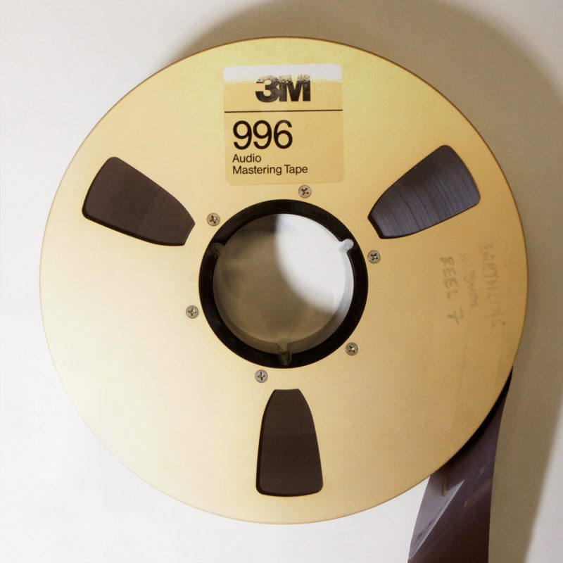 gold-coloured metal audio mastering tape reel, labelled 3M 996, containing 2 inch dark brown tape