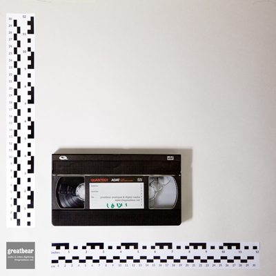 Black plastic cassette tape with rulers showing dimensions: 18.7 × 10.2cm (7​1⁄3 × 4 inch)