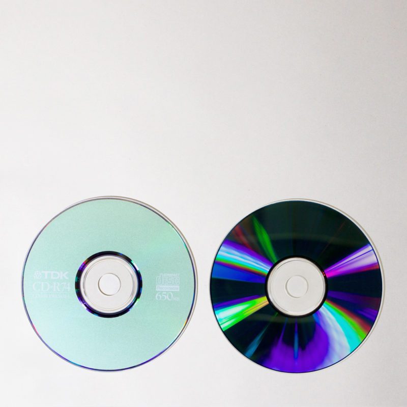 2 discs, one printed: TDK CDR74, the other showing shiny purple surface with rainbow-coloured reflections