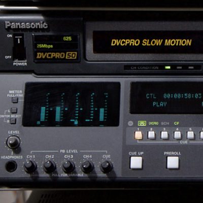Dark grey rack-mounted machine with multiple buttons, dials and displays with text: DVCPRO SLOW MOTION