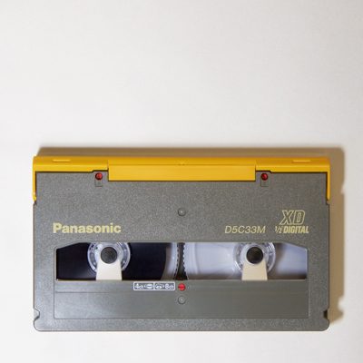 light grey and yellow rectangular D-5 video cassette D5C33M, with notched lower corners