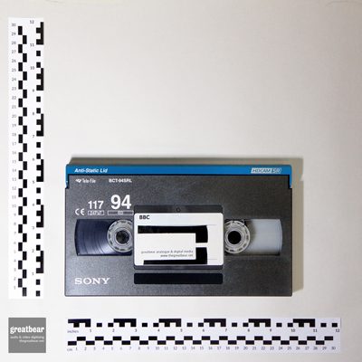 dark grey and blue rectangular HDCAM cassette with rulers indicating width 25.3 cm by height14.4 cm.