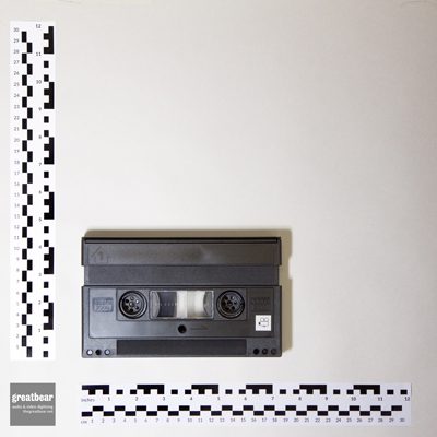 black rectangular Video 2000 cassette with rulers indicating width 18.3 cm by height 10.1 cm.