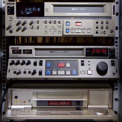 3 rack-mounted S-VHS and D-VHS recorders with multiple buttons, knobs and displays