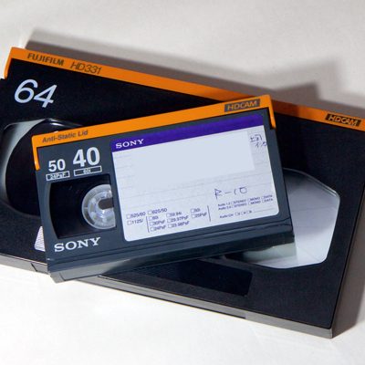 smaller Sony HDCAM video cassette on top of larger - both dark grey and orange
