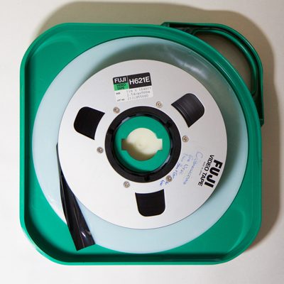 dark brown / black 1 inch video tape on aluminium spool in green plastic case with inbuilt handle