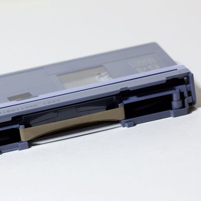 end view of cassette with protective shield opened to reveal shiny black tape