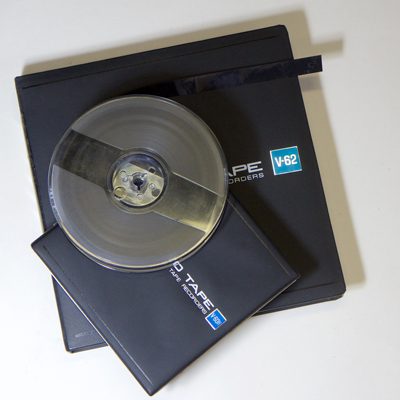 5" diameter spool of ½ inch video tape resting on 2 boxes, one larger