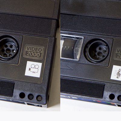 one side of Video 2000 cassette showing label with film camera graphic; other side of same tape showing label with treble clef graphic