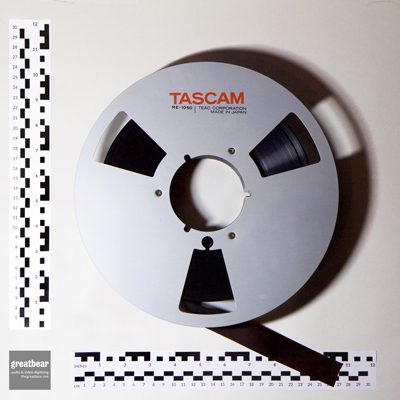 Aluminium Tascam spool with one inch brown magnetic tape and rulers indicating dimensions