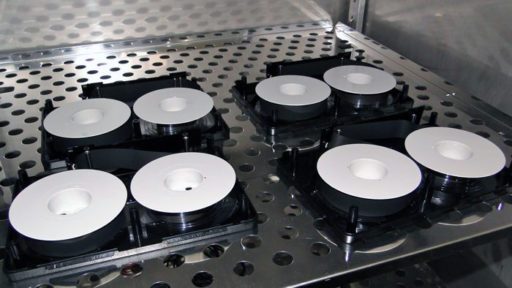 multiple open video cassettes with black tape on white spools, lying on metal shelf inside incubator