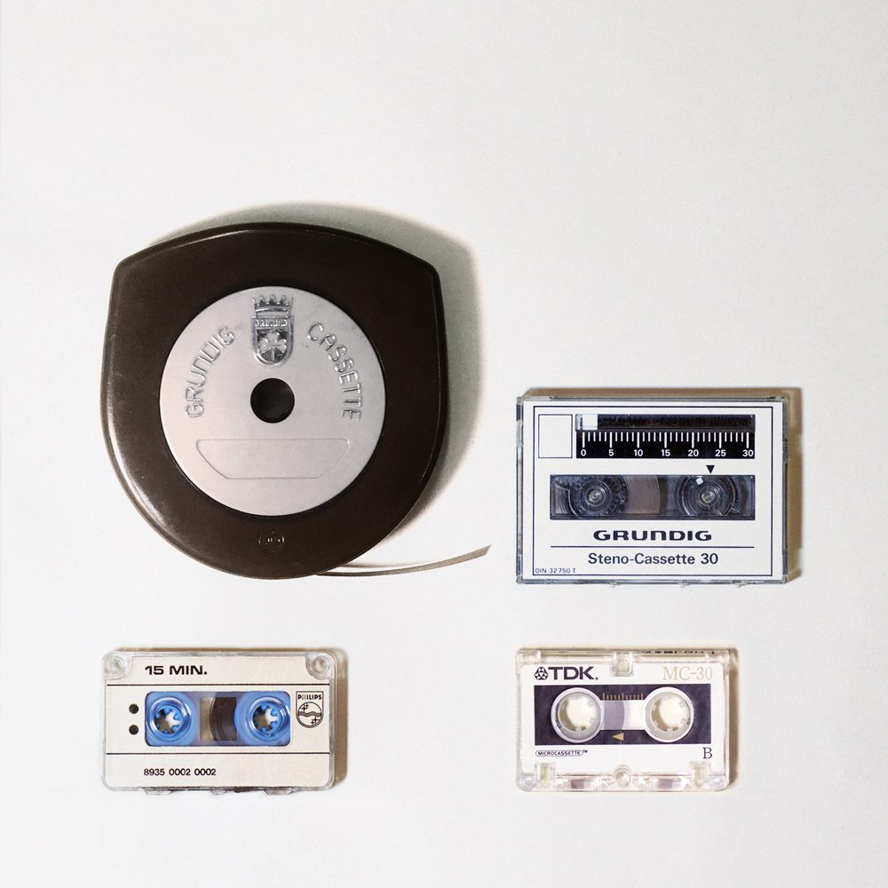 4 small cassettes of differing dimensions: opaque plastic arch-shaped Grundig Stenorette tape cassette; rectangular clear plastic Grundig Steno-Cassette with ruler strip; miniature,rectangular clear plastic TDK microcassette; miniature, rectangular clear plastic Philips minicassette