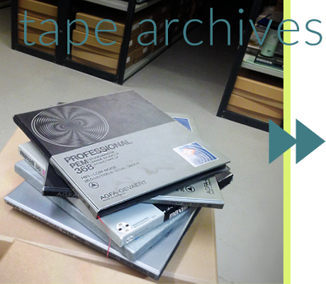 Text: tape archives. Image: pile of large square tape boxes in archive warehouse